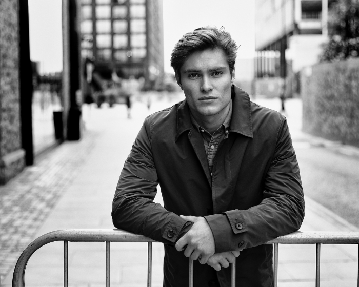 Dark outside black and white portrait photo of white male leaning on a railing.